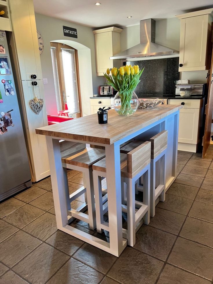 a kitchen island with stools in front of it and flowers on the counter top