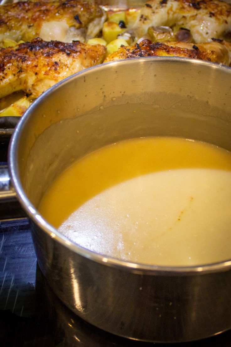 a pan filled with soup sitting on top of a stove next to another pan full of food