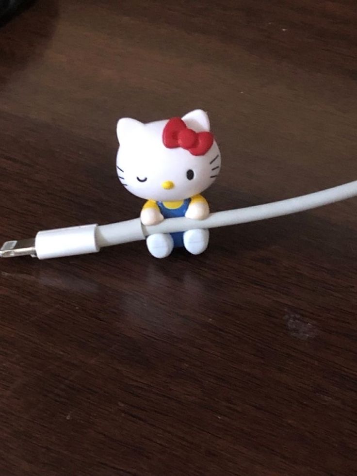 a hello kitty toy sitting on top of a wooden table next to a charger