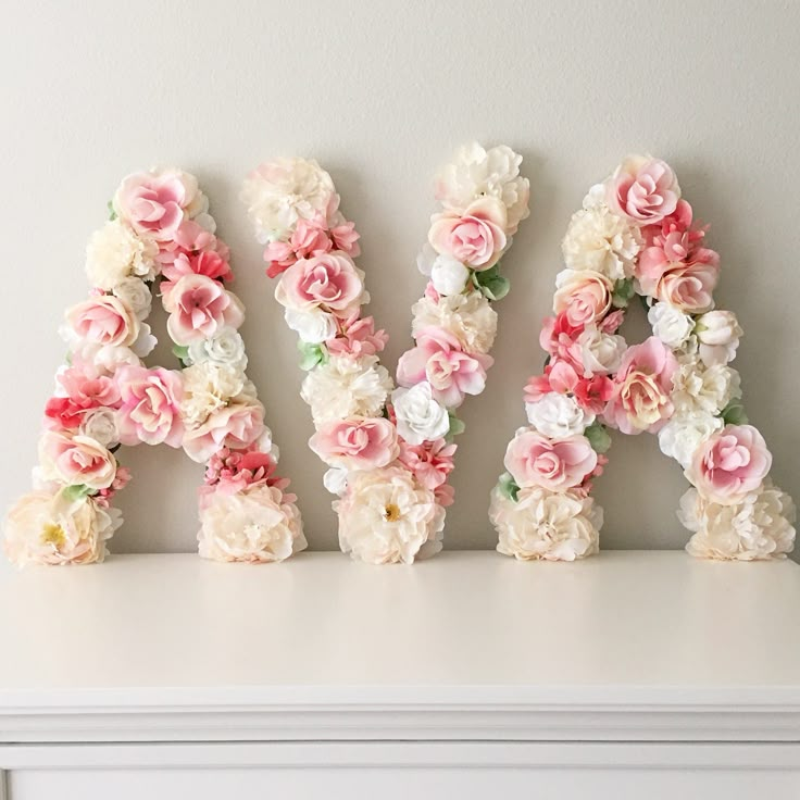 the letters are made out of flowers on top of a white shelf in front of a wall