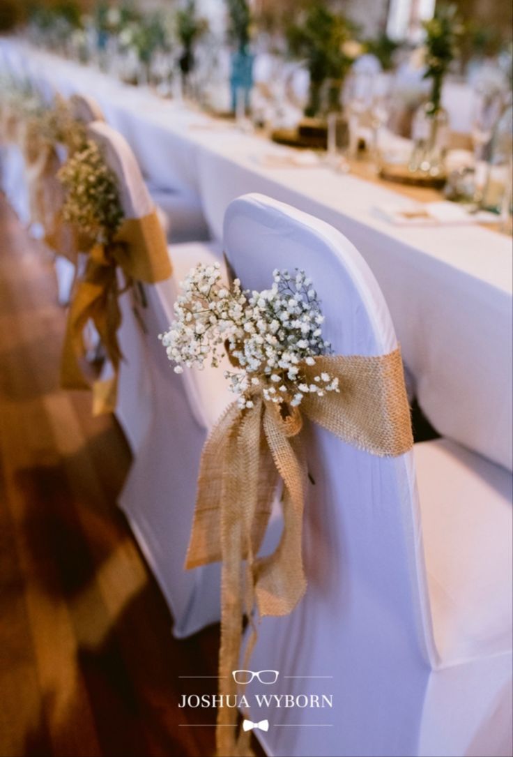 the chairs are decorated with baby's breath flowers and burlap ribbons for an elegant touch