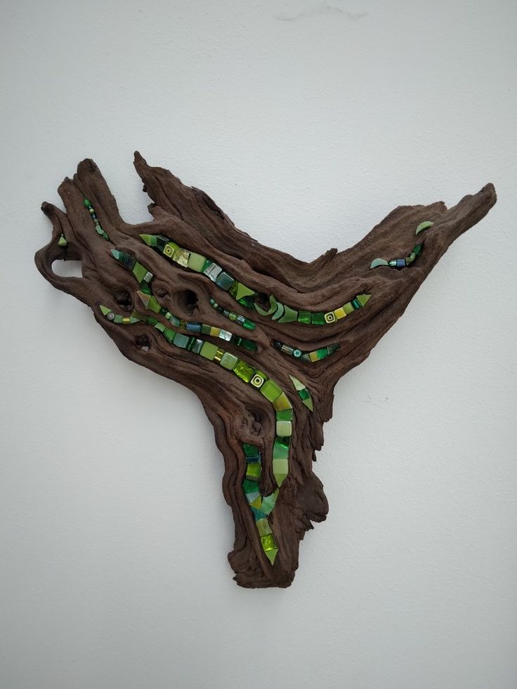 a piece of driftwood with green and yellow glass pieces on it's sides