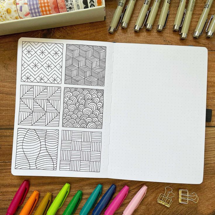 an open notebook with several different patterns on it next to markers, pens and pencils