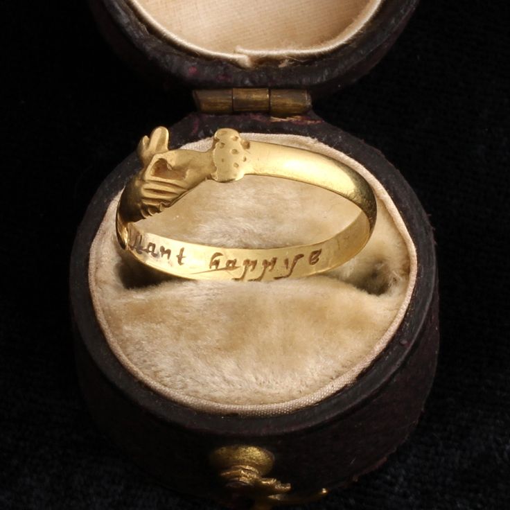 The symbol of two clasped hands is an ancient, sentimental design that has historically been associated with fidelity and marriage. "Fede" rings (from the Italian, for "trust" or "fidelity") or "Gimmel" rings (meaning "twin") were often used as betrothal tokens in 16th and 17th century Europe, but they remained popular until well after the Renaissance. This wonderful 18th century fede ring with a heart emerging from the pair of hands is also a posy ring inscribed with the words "constant happye" Antique Engraved Open Ring For Ceremonial Occasions, Antique Hand Forged Rings For Ceremonial Occasions, Antique Hand Forged Ceremonial Rings, Symbolic Engraved Rings For Ceremonial Occasion, Symbolic Ceremonial Engraved Rings, Antique 14k Stamped Jewelry For Ceremonial Occasions, Vintage Open Ring For Ceremonial Occasions, Symbolic 14k Stamped Promise Jewelry, Symbolic 14k Engraved Promise Ring