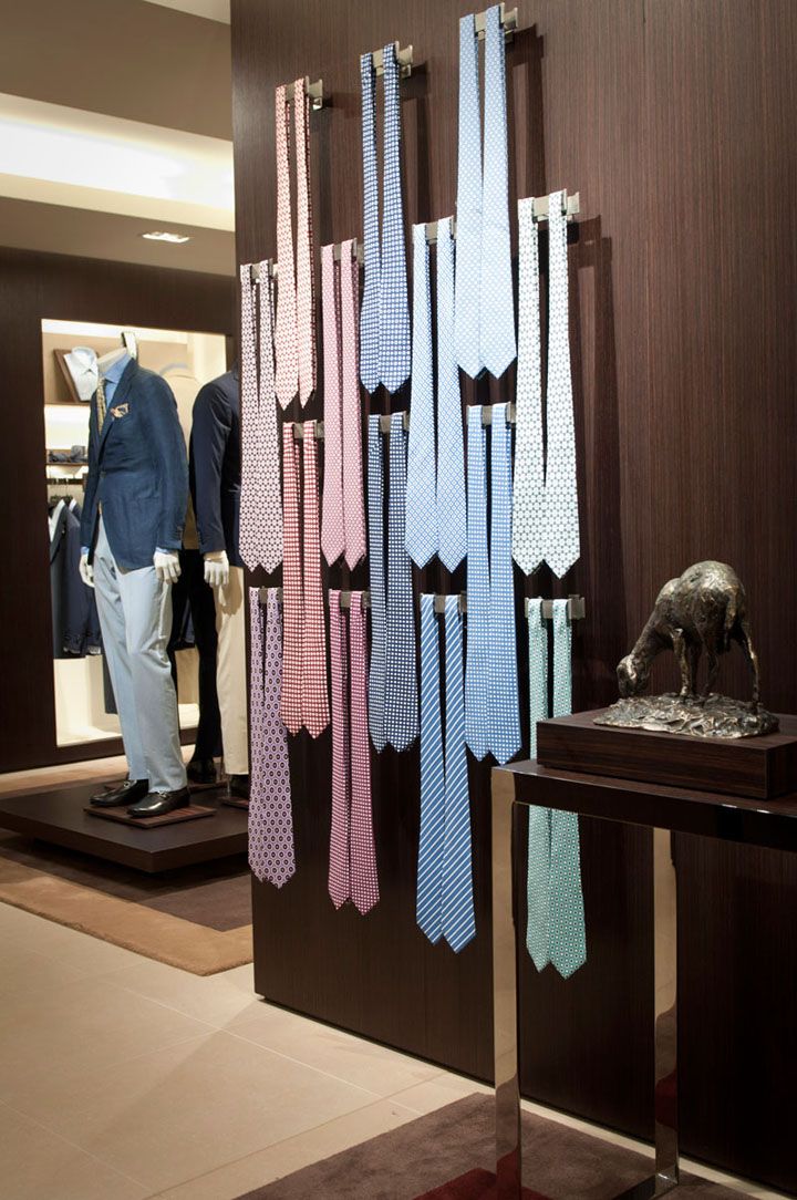 several different colored ties hanging on display in a store window with mannequins behind them