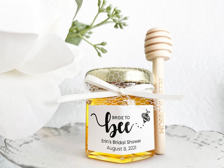 a jar of honey with a wooden stick next to it on a white tablecloth