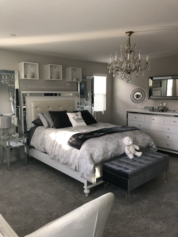 a bedroom with a bed, dresser and mirror in the corner on the wall above it is a chandelier that hangs from the ceiling