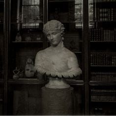 an old photo of a busturine in front of bookshelves