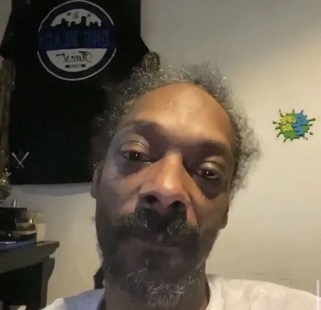 a man with curly hair and beard wearing a white shirt is looking at the camera