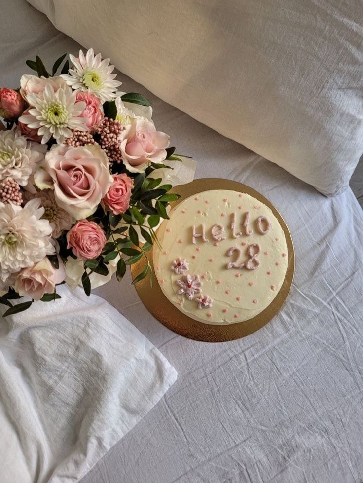 a bouquet of flowers next to a cake on a bed