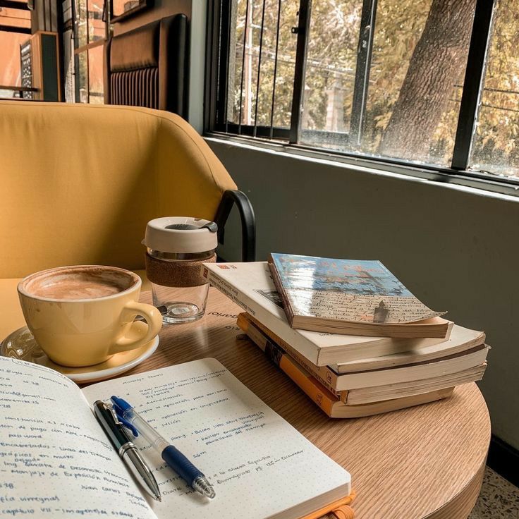 a cup of coffee and some books on a table