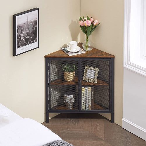 a small shelf with books and flowers on it in the corner of a room next to a bed