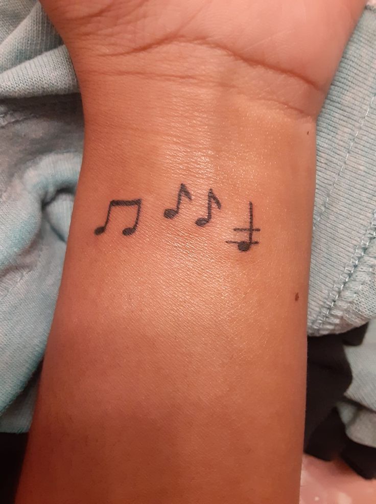 a wrist tattoo with musical notes on it