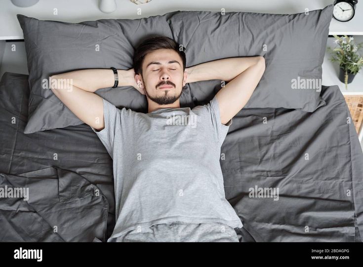 a man laying in bed with his head on the pillow - stock image