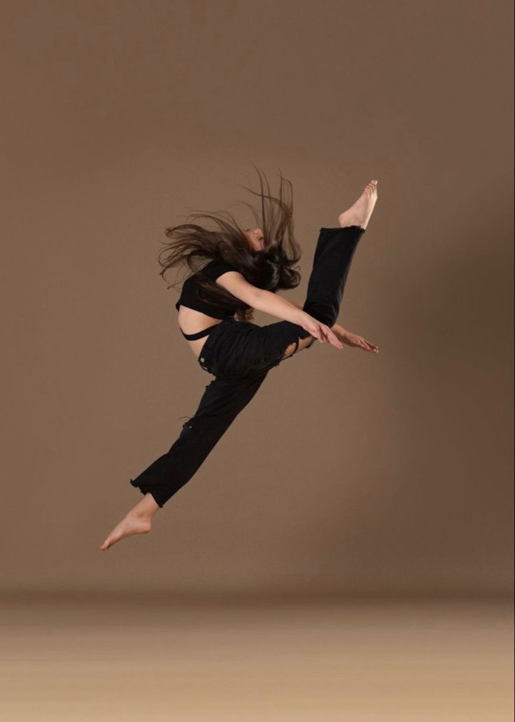 a woman is jumping in the air with her hair flying through the air while wearing black clothing