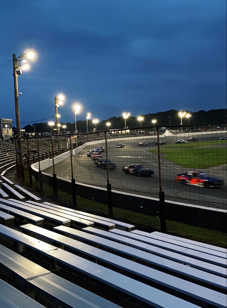 the cars are racing on the track in the evening at the race track with lights