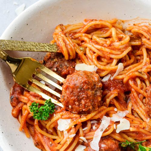 a white bowl filled with spaghetti and meatballs