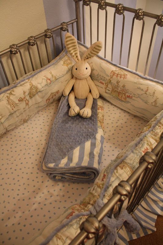 a stuffed animal sitting on top of a blanket in a crib