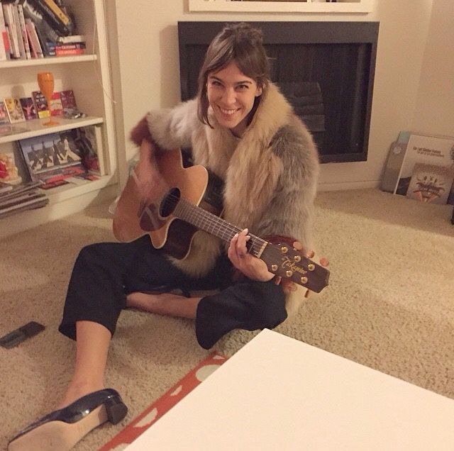 a woman sitting on the floor playing a guitar