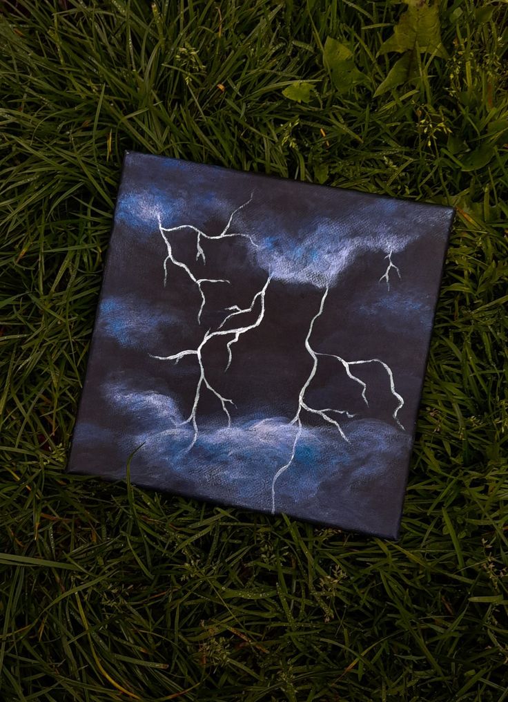 a piece of art that is laying in the grass with some lightnings on it