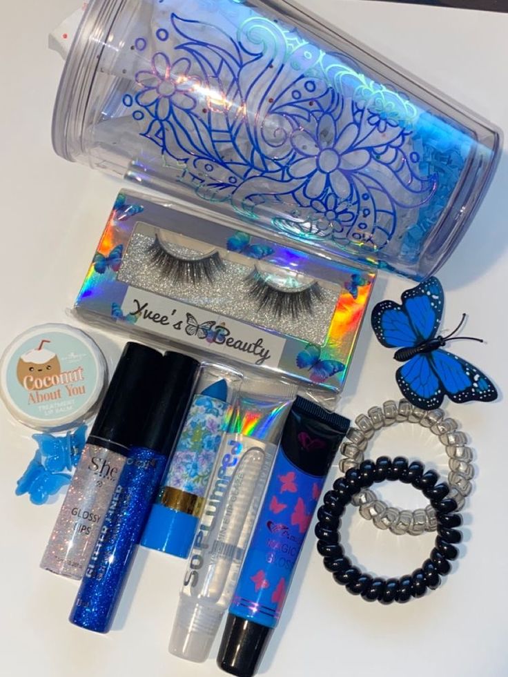 an assortment of makeup and accessories on a white surface with butterfly decoration around the eyes