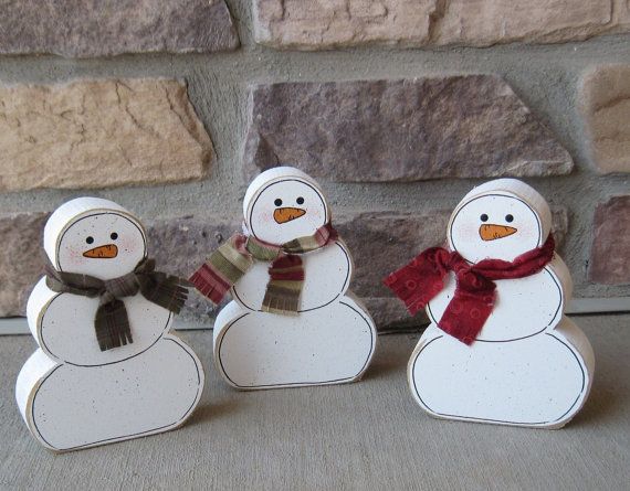 three snowmen are standing in front of a brick wall