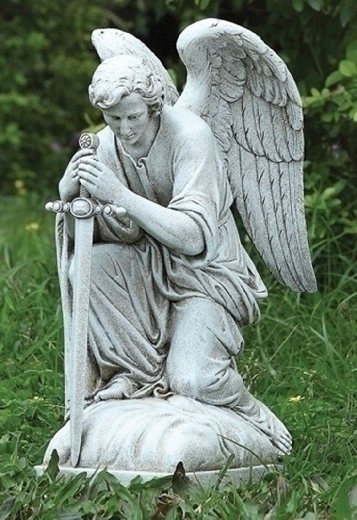 an angel statue sitting on top of a lush green field