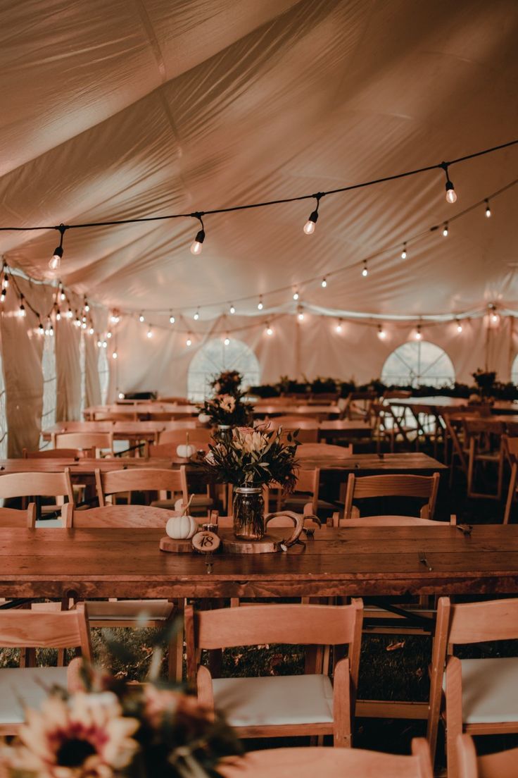 tables and chairs are set up in a tent with lights strung over the top of them