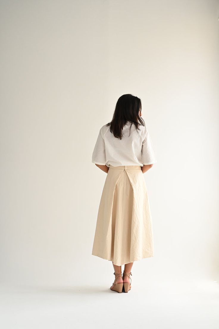 Casey Casey Moon Skirt in Ecru. Pleated skirt in washed cotton with a tailored waist and back button and zip closure. Front pleats hide pockets, while the back pleat creates volume. Lined in cotton. 99% cotton, 1% polyester, 100% cotton lining. Made in France. XS - 27" waist, 33" lengthS - 28" waist, 34" length Cotton Gathered Skirt Bottoms For Work, Cotton Pleated Skirt With Relaxed Fit, Cotton Relaxed Fit Pleated Skirt, Relaxed Fit Cotton Pleated Skirt, Cream Asymmetrical Relaxed Skirt, Relaxed Fit Flared Skirt For Work, Workwear Relaxed Fit Flared Skirt, Chic Cotton Skirt With Pleated Hem, Beige Pleated Asymmetrical Skirt