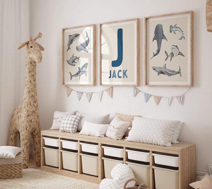 a nursery room with three pictures on the wall and two stuffed animals hanging above it