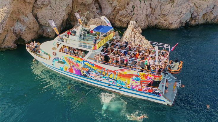 a boat full of people is in the water near some rocks and another boat with passengers