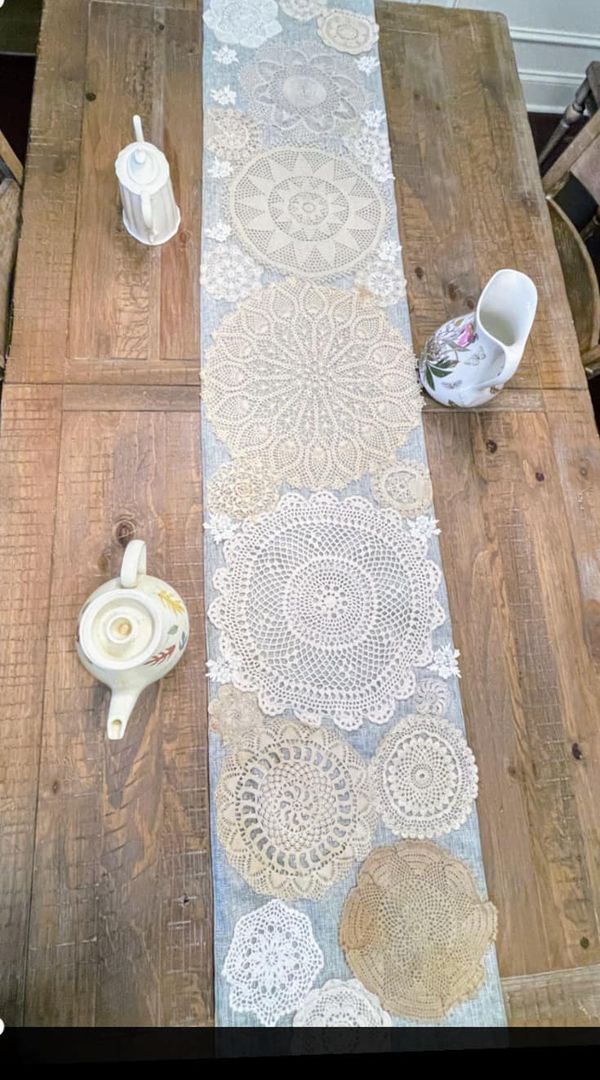 a wooden table topped with white doily next to cups