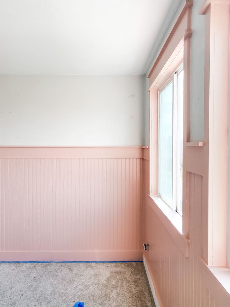 an empty room with pink paint on the walls and blue tape taped to the floor