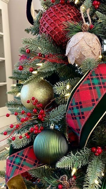 a christmas tree decorated with plaid ribbon and green, red, and gold baubles