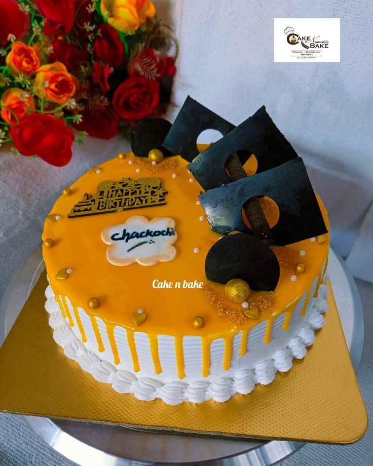 a cake with yellow frosting and black decorations on the top is sitting on a gold plate