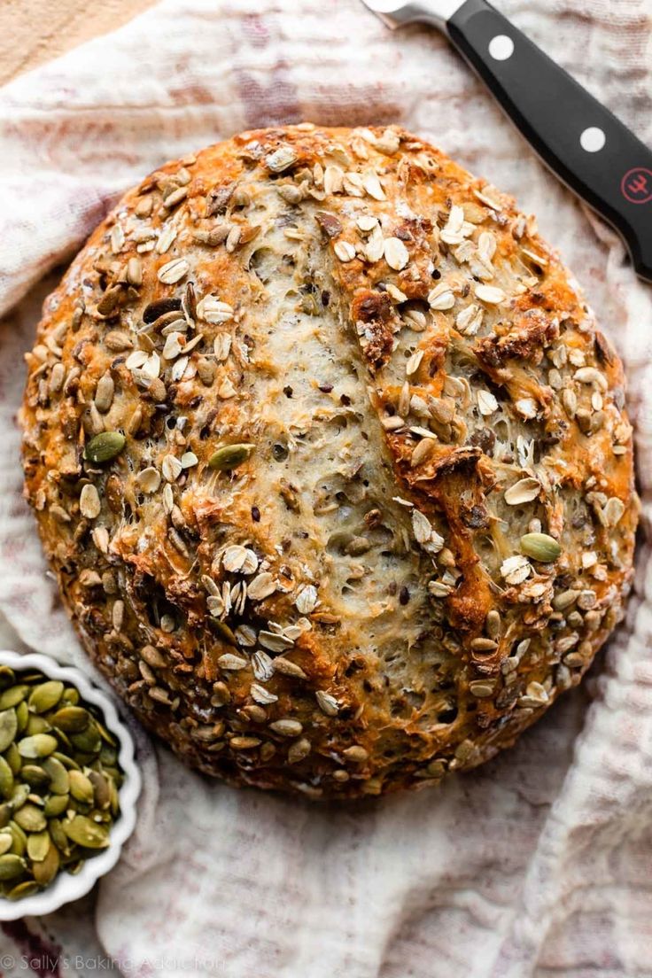 a loaf of bread sitting on top of a table next to two bowls filled with seeds