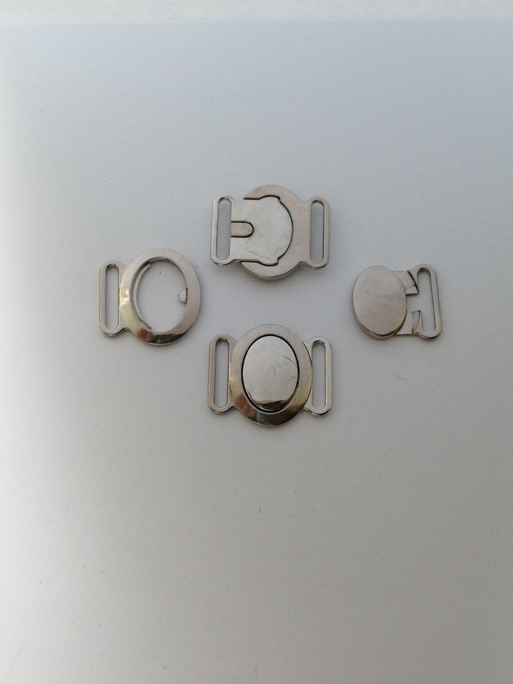 four pieces of metal sitting on top of a white surface with the letters g and l