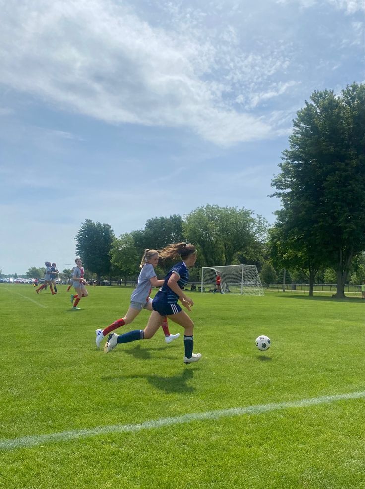 two girls are playing soccer on the field