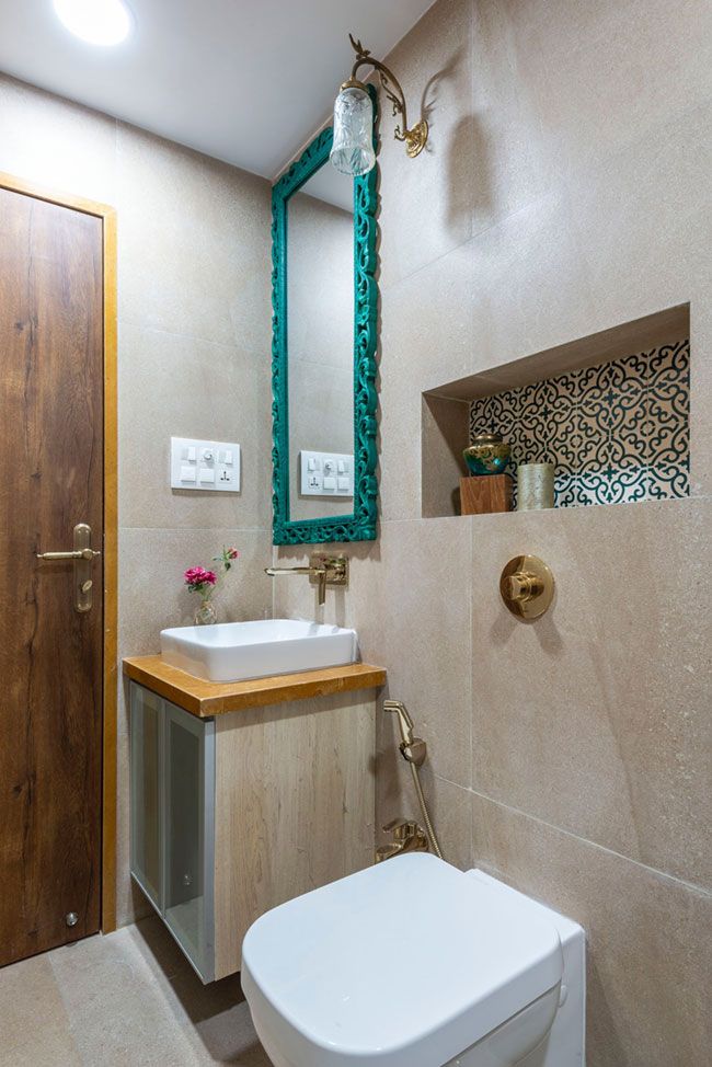 a white toilet sitting next to a bathroom sink under a mirror and wooden cabinet above it