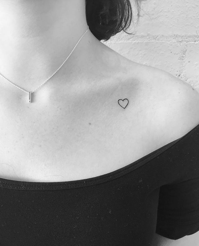 a black and white photo of a woman's chest with a heart tattoo on it