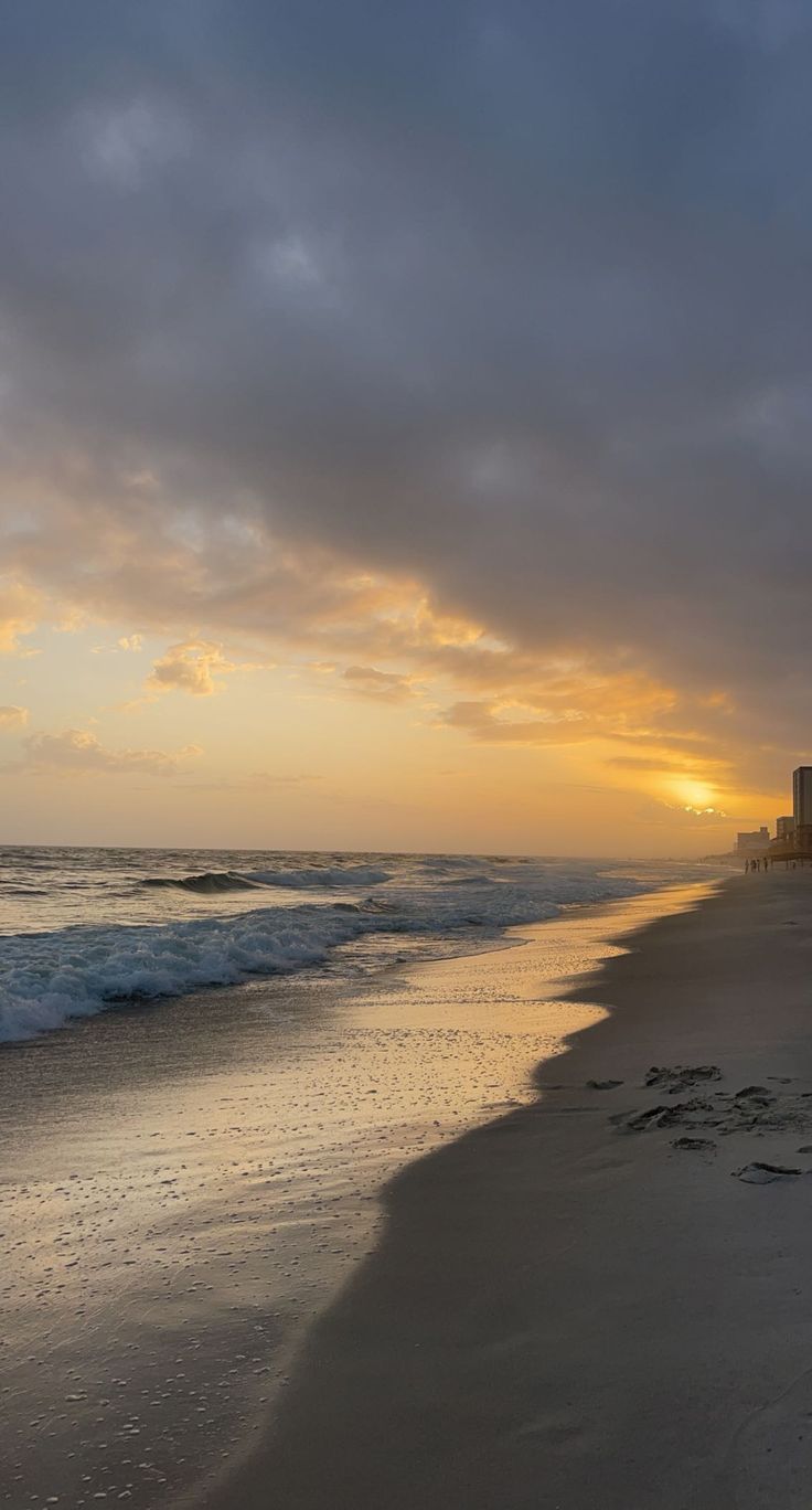 the sun is setting at the beach with waves coming in