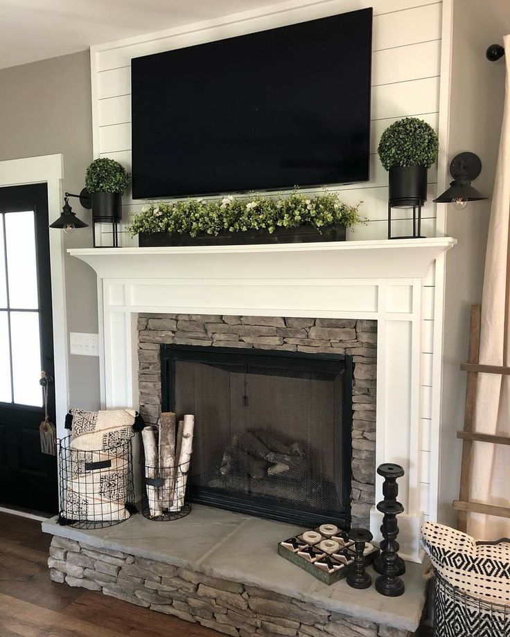 a fireplace with a flat screen tv above it and other decorations on the mantel