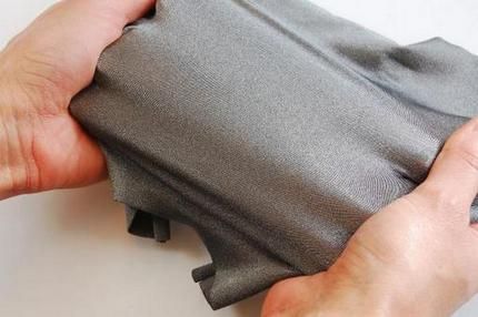 a person is opening up a piece of gray material with their hands on it and the fabric has been folded