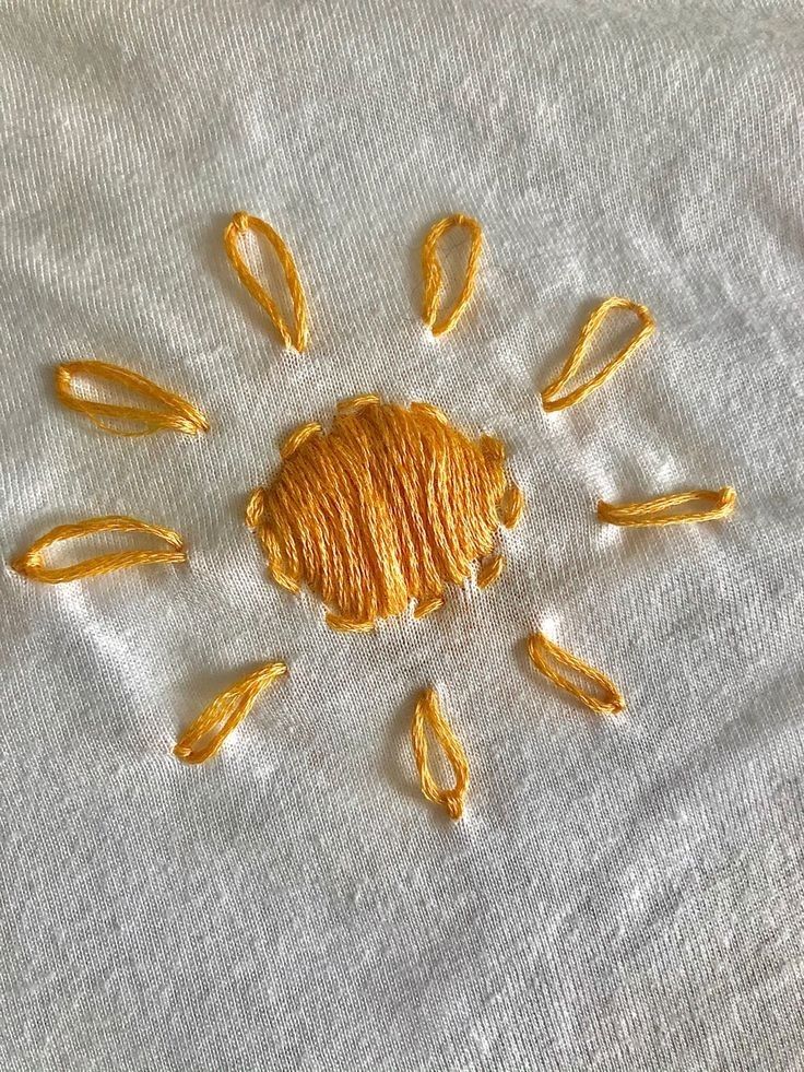 the sun is made out of yellow thread on a white cloth with holes in it