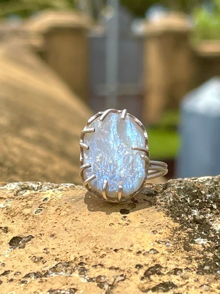 Sri Lankan Raw Moonstone & Silver Ring Handmade ring made by one of our favorite artisans, Kalumali, who comes from a family making jewelry for generations. He hand picks this stunning, glistening raw moonstone and wire claws the stone in .925 silver. The end product is a special, unique piece of jewelry from Sri Lanka. When I see moonstones I think of Sri Lanka because there is a deep connection with the moon in this culture. The semi-circular moonstone, a common architectural feature in many temples in Sri Lanka, is called Sandakada Pahana in Singhala and symbolises Samsara, the endless cycle of birth and the pains associated with it.Furthermore, Poya is the name given to the Lunar monthly Buddhist holiday of Uposatha in Sri Lanka.Poya, when the moon is full, is considered a civil and ba Spiritual Large Stone Sterling Silver Moonstone Ring, Spiritual Large Stone Moonstone Ring In Sterling Silver, Spiritual Moonstone Ring With Large Stone In Sterling Silver, Spiritual Sterling Silver Moonstone Ring With Large Stone, Unique Large Moonstone Ring, Unique Moonstone Ring With Large Stone, Adjustable Large Stone Moonstone Ring In Sterling Silver, Adjustable Sterling Silver Moonstone Ring With Large Stone, Hand Forged Moonstone Ring For Gift