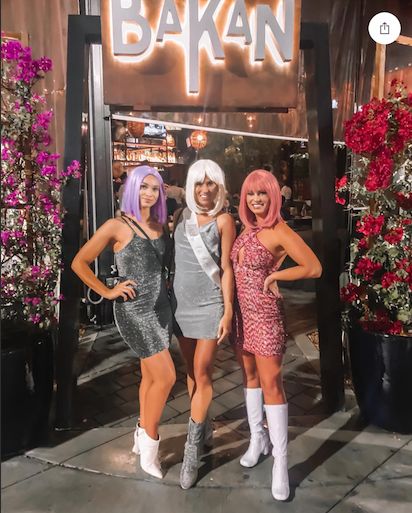 three women standing in front of a sign that says bakan