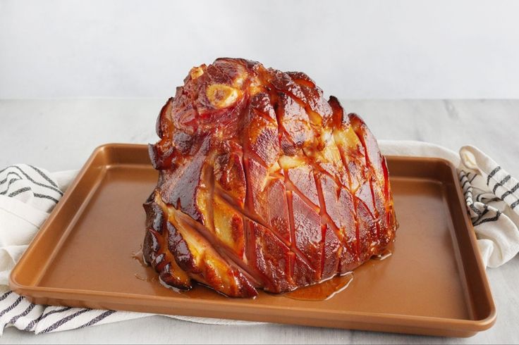 a large piece of meat sitting on top of a brown tray next to a fork