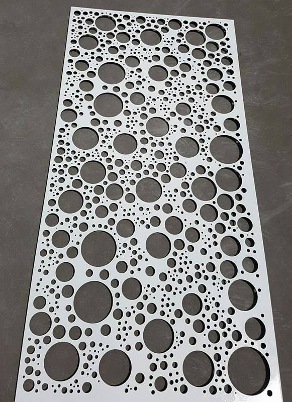 a metal grate with holes and circles on the bottom, sitting on a gray surface