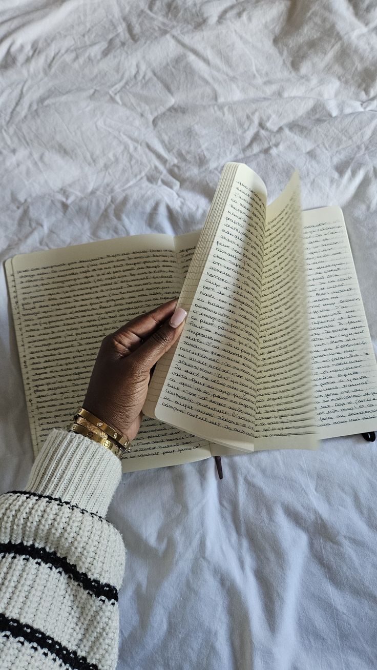 a person reading a book on top of a bed