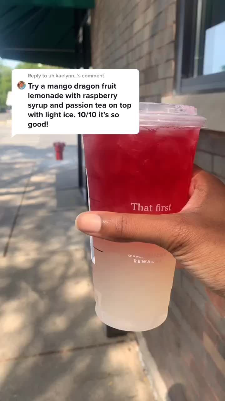 a person holding up a cup with red liquid in it on the side of a building